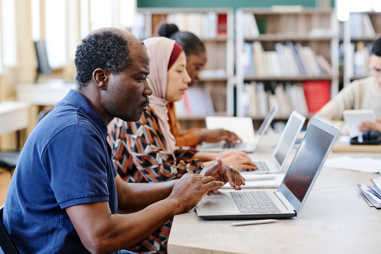 women and man work from laptops in a library