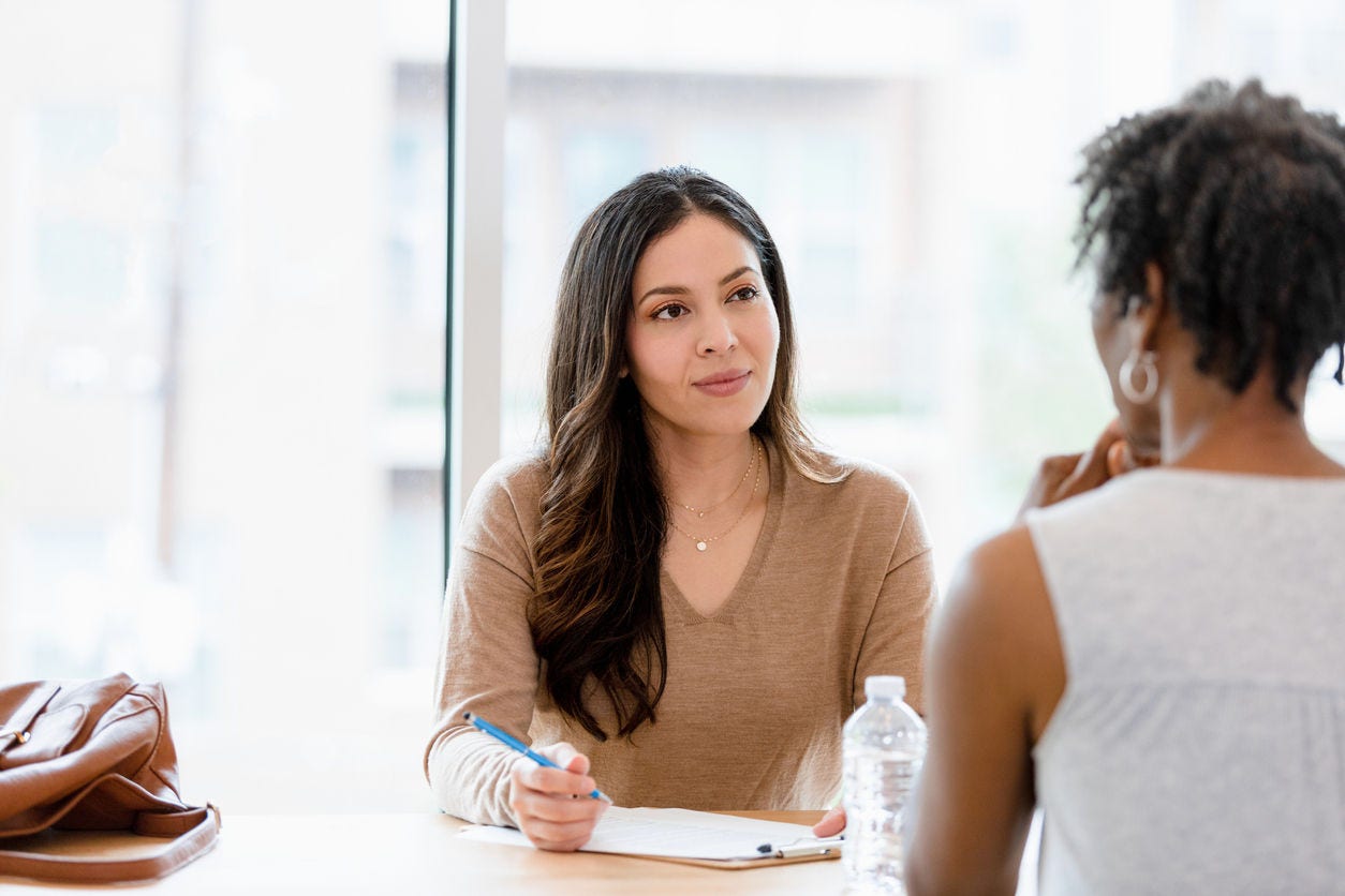 The mid adult female counselor keeps a pleasant look on her face as she listens to the unrecognizable female client.