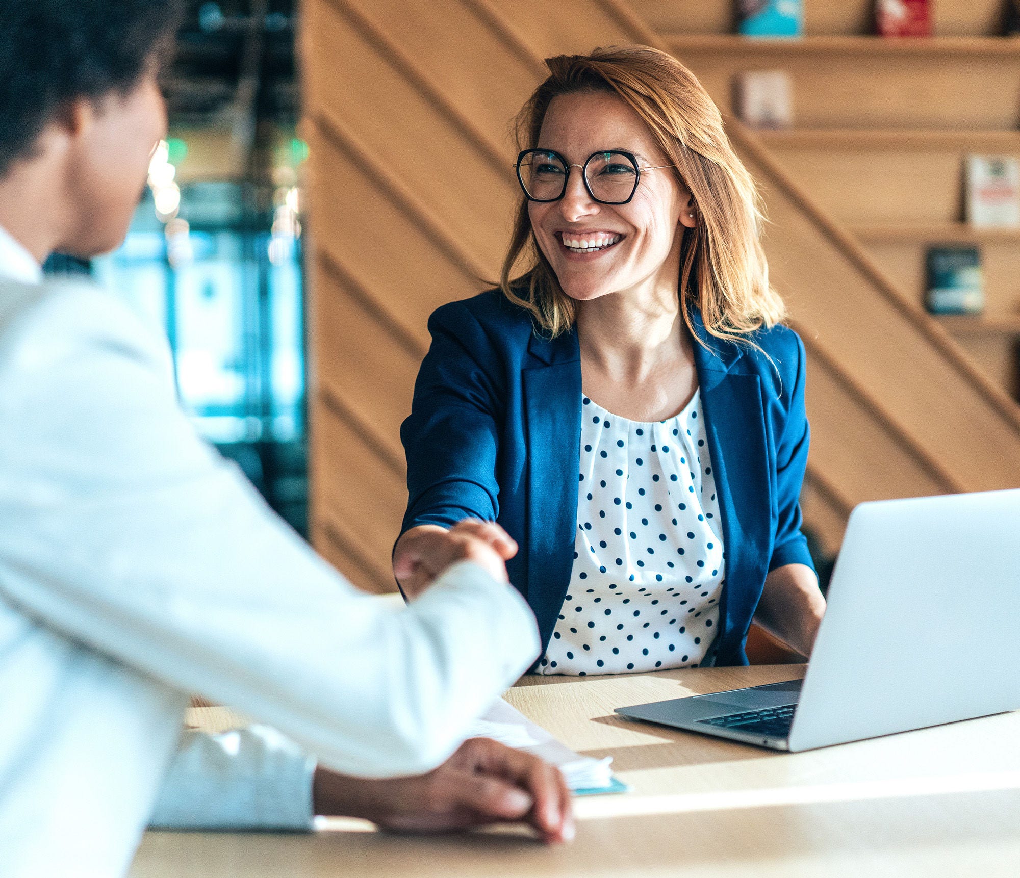 Happy businesswoman and businessman shaking hands at meeting. Professional business executive leaders making handshake agreement. Happy business man closing deal at negotiations 