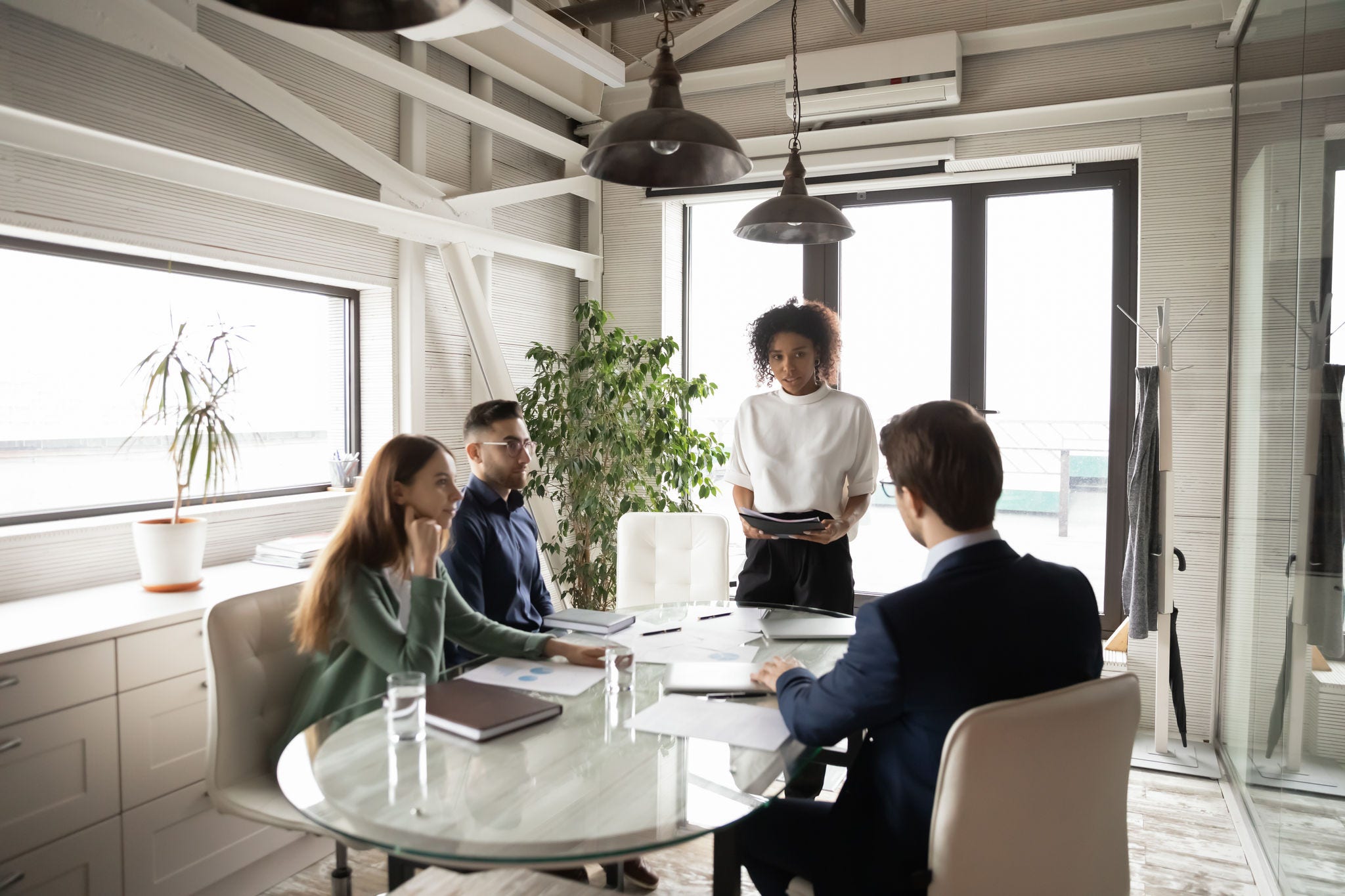 Confident African American businesswoman leading briefing, explaining strategy, training diverse staff sitting at table in boardroom, group negotiations, business partners sharing startup ideas