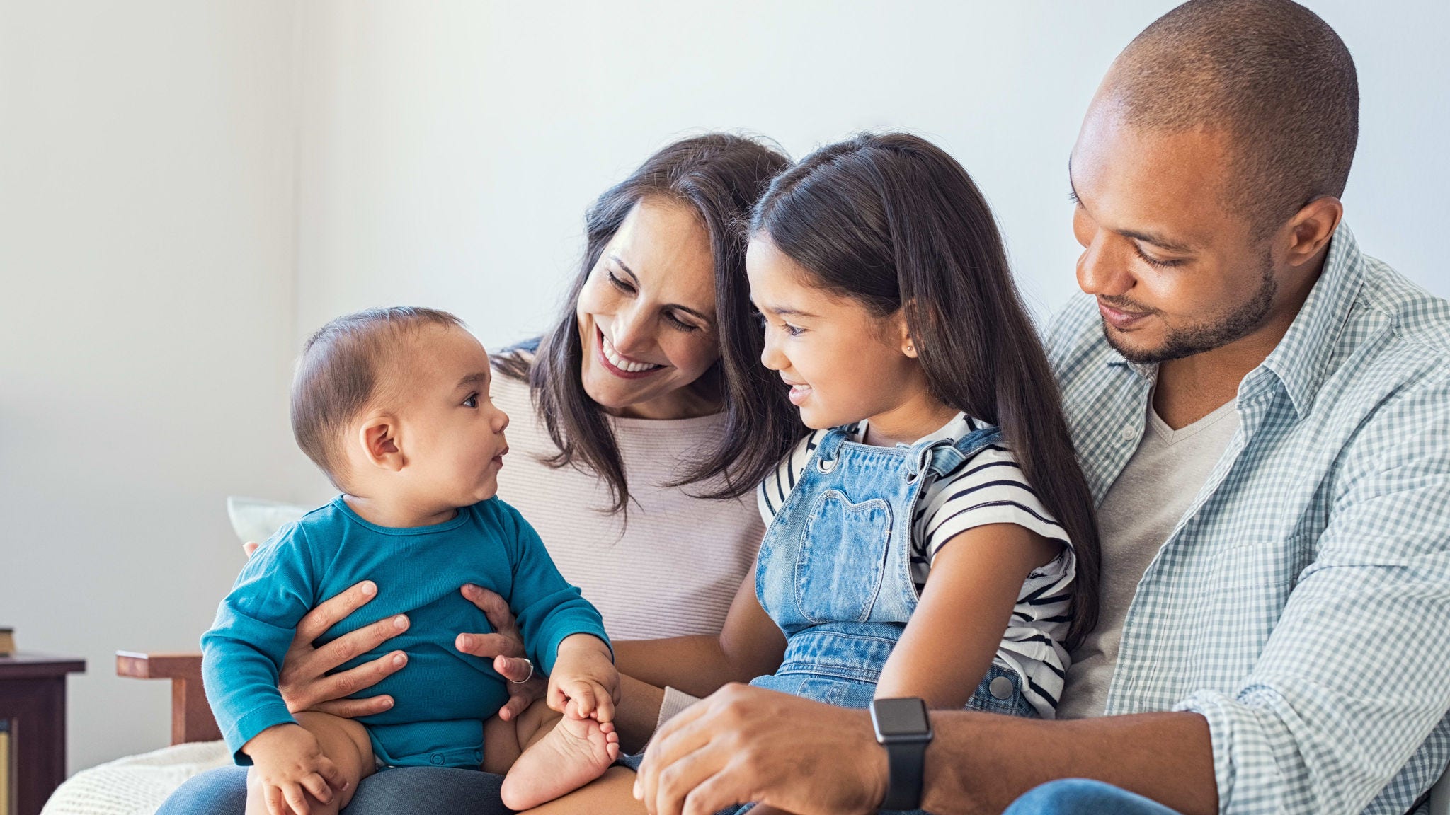 A family is sitting on a couch with a baby.