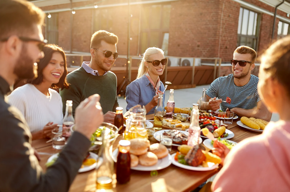 Group of people sitting outside enjoying a meal in the sun