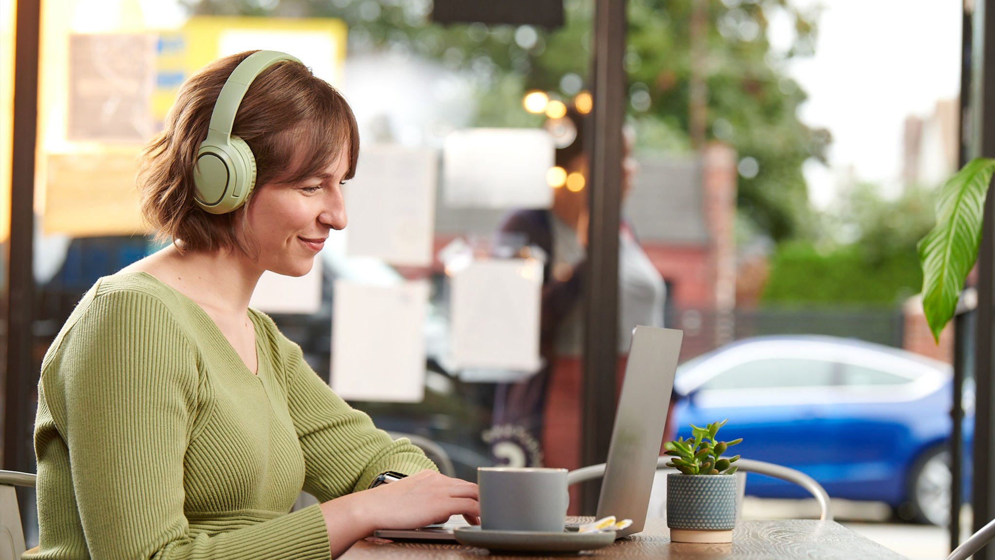 Woman smiles on a virtual meeting in a coffee shop.