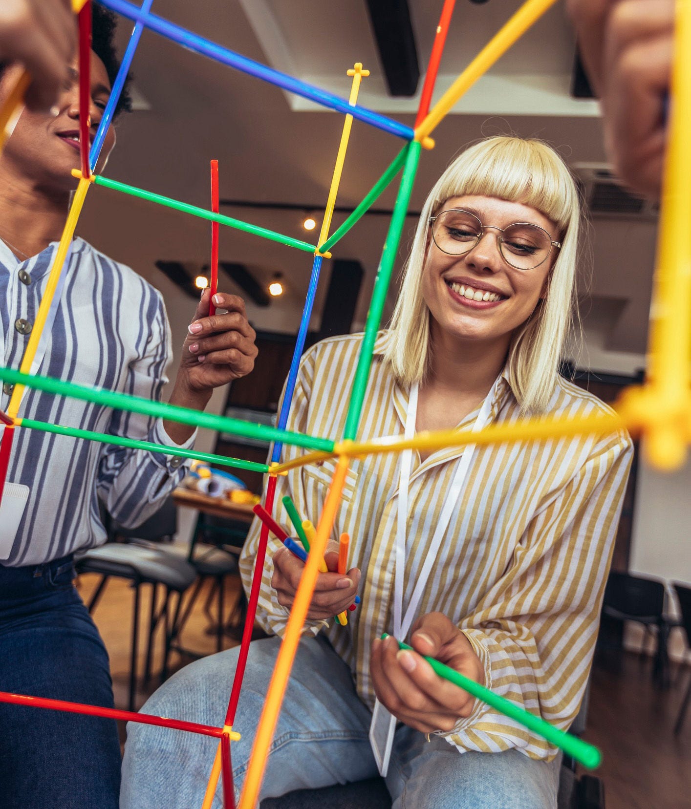 coworkers playing team building game together with colored plastic rods