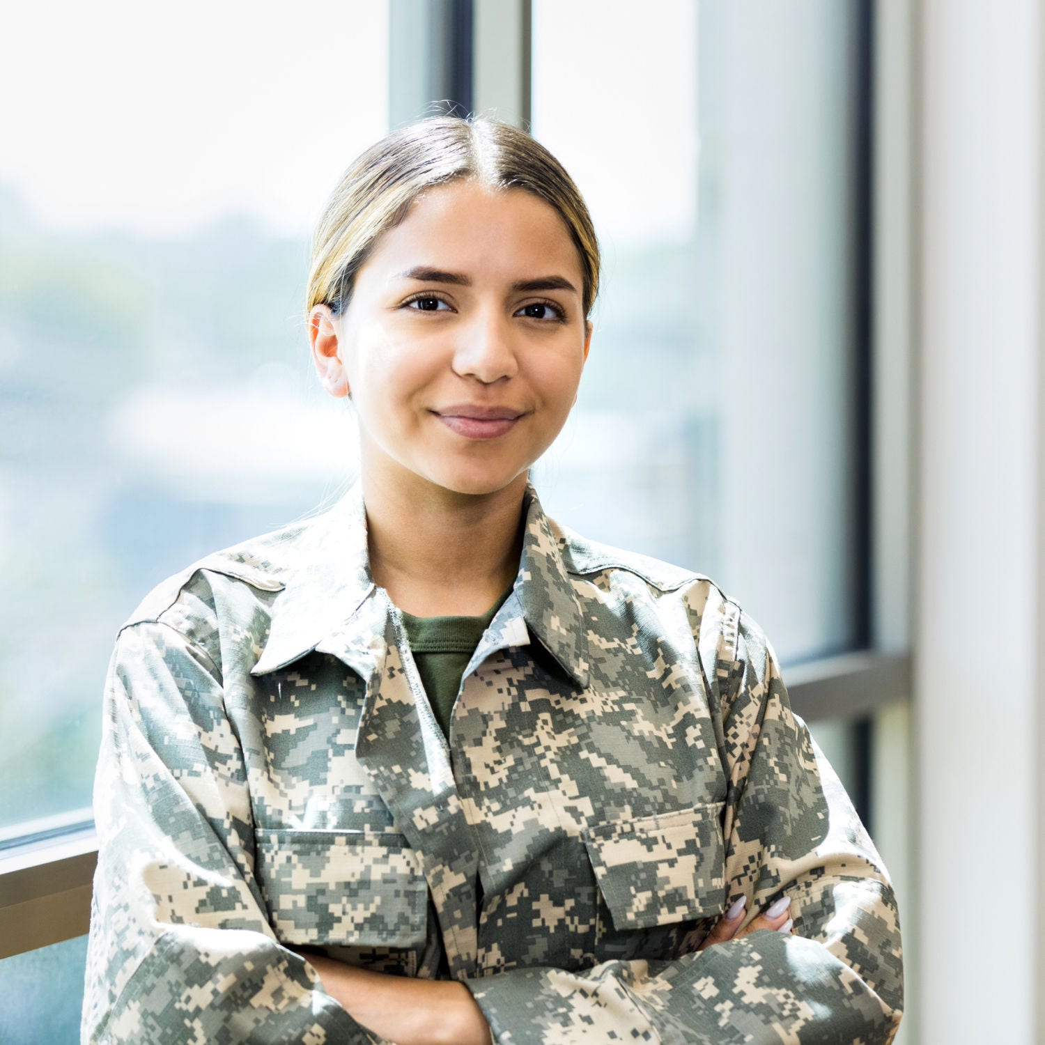 female veteran smiling in front of a window crossing her arms