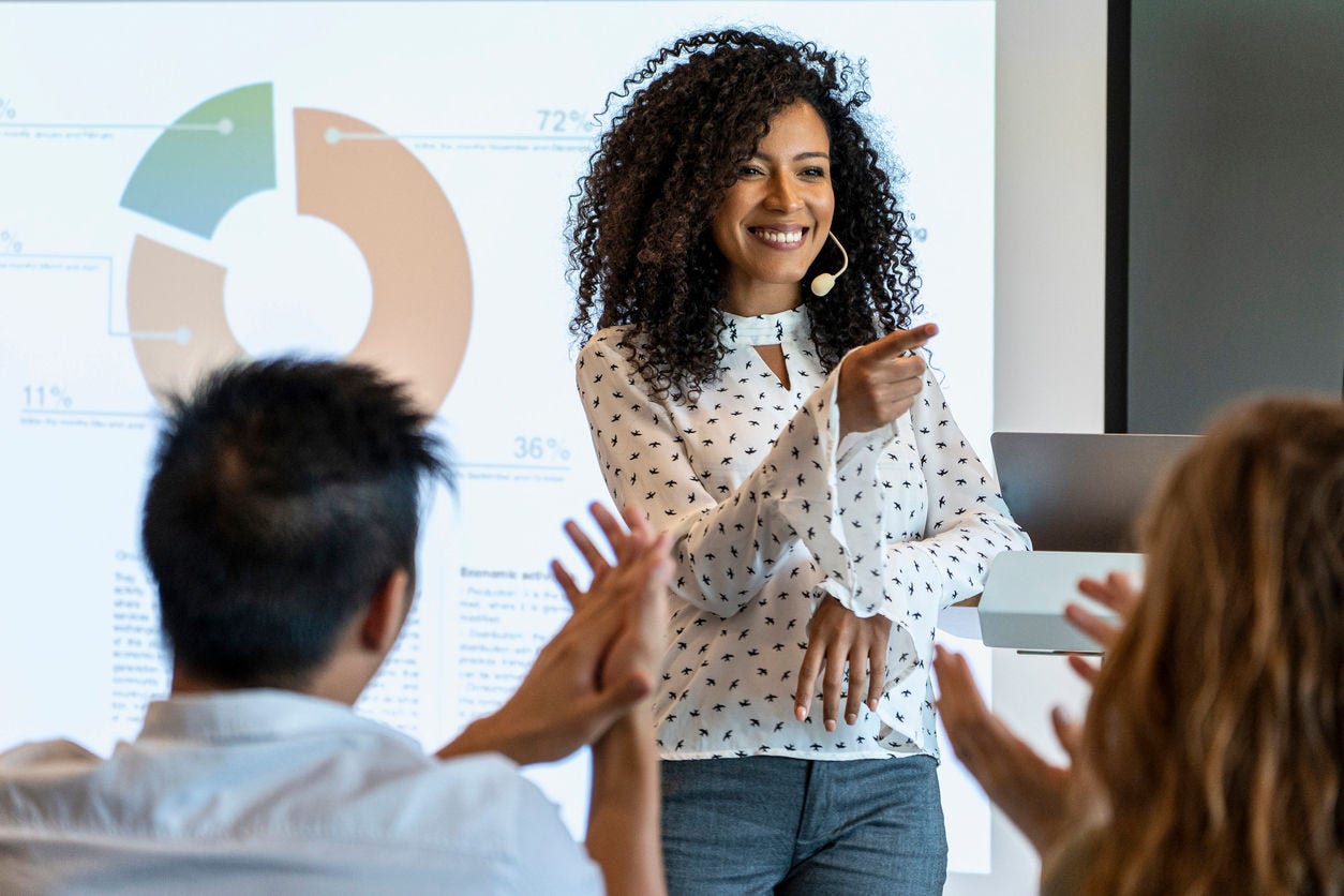 Business people clapping after young businesswoman finished presentation in board room