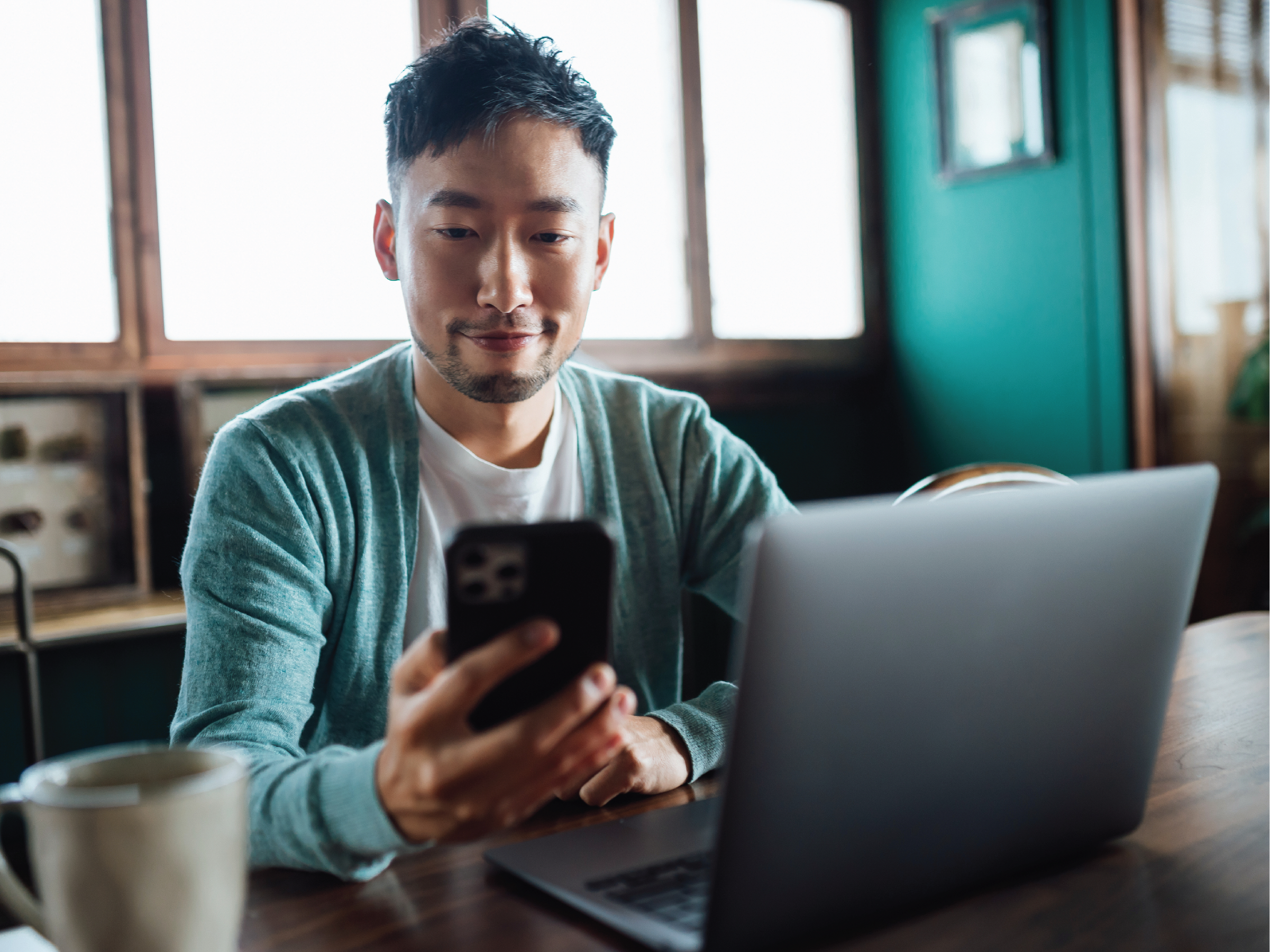 man holding phone in front of laptop