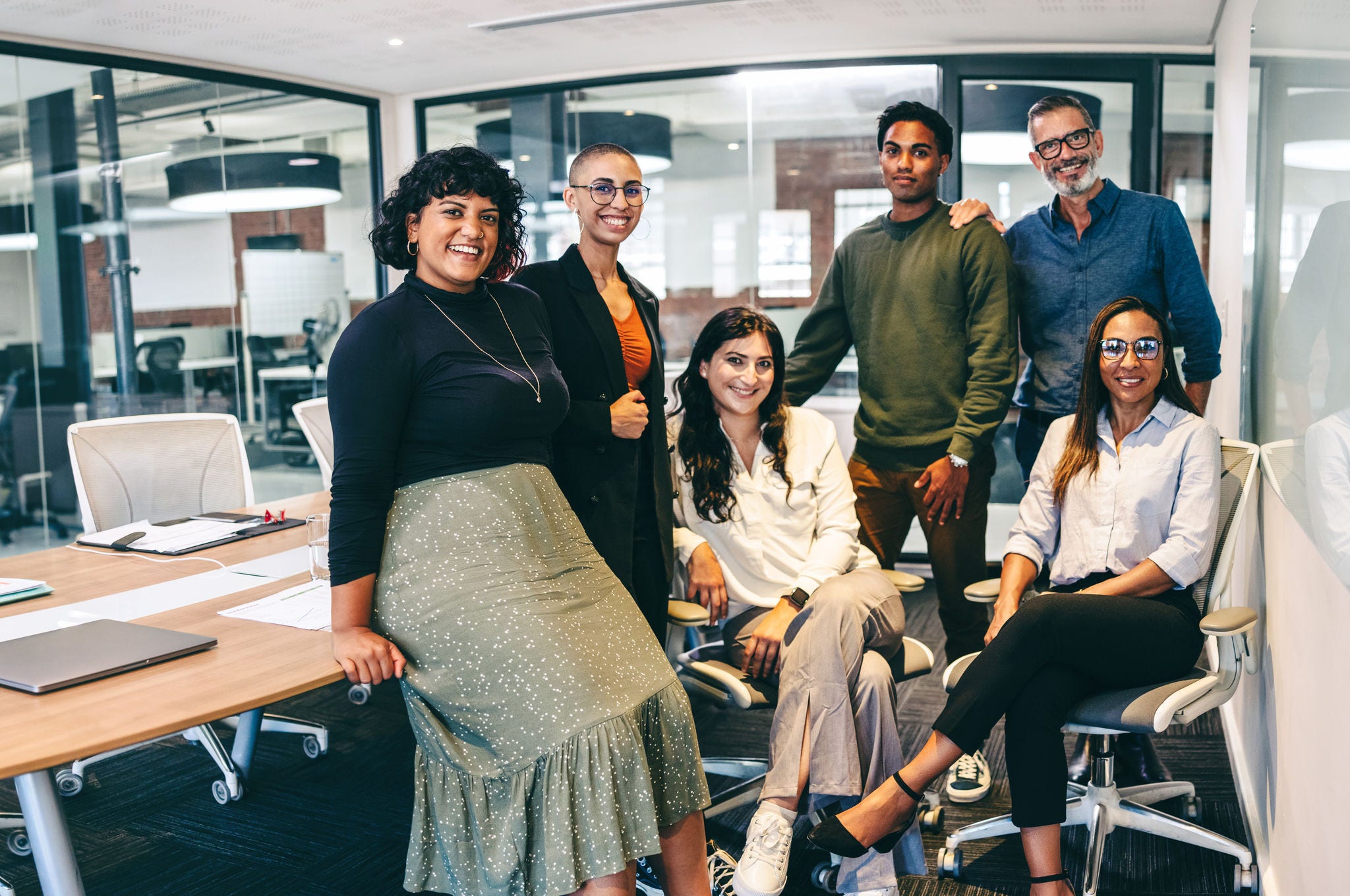 Team of businesspeople smiling at the camera in a boardroom. Cheerful businesspeople grouped together in a modern workplace. Diverse team of businesspeople looking cheerful.