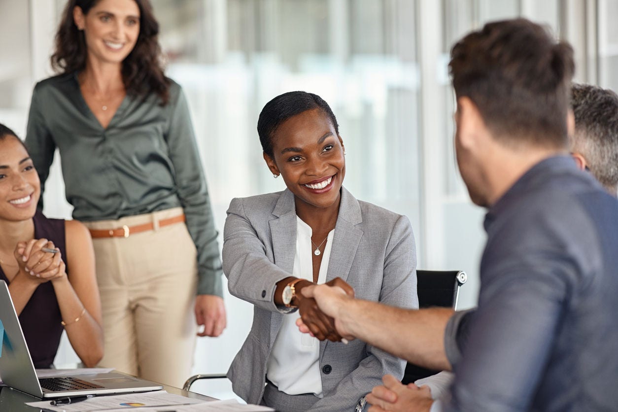 Happy businesswoman and businessman shaking hands at meeting