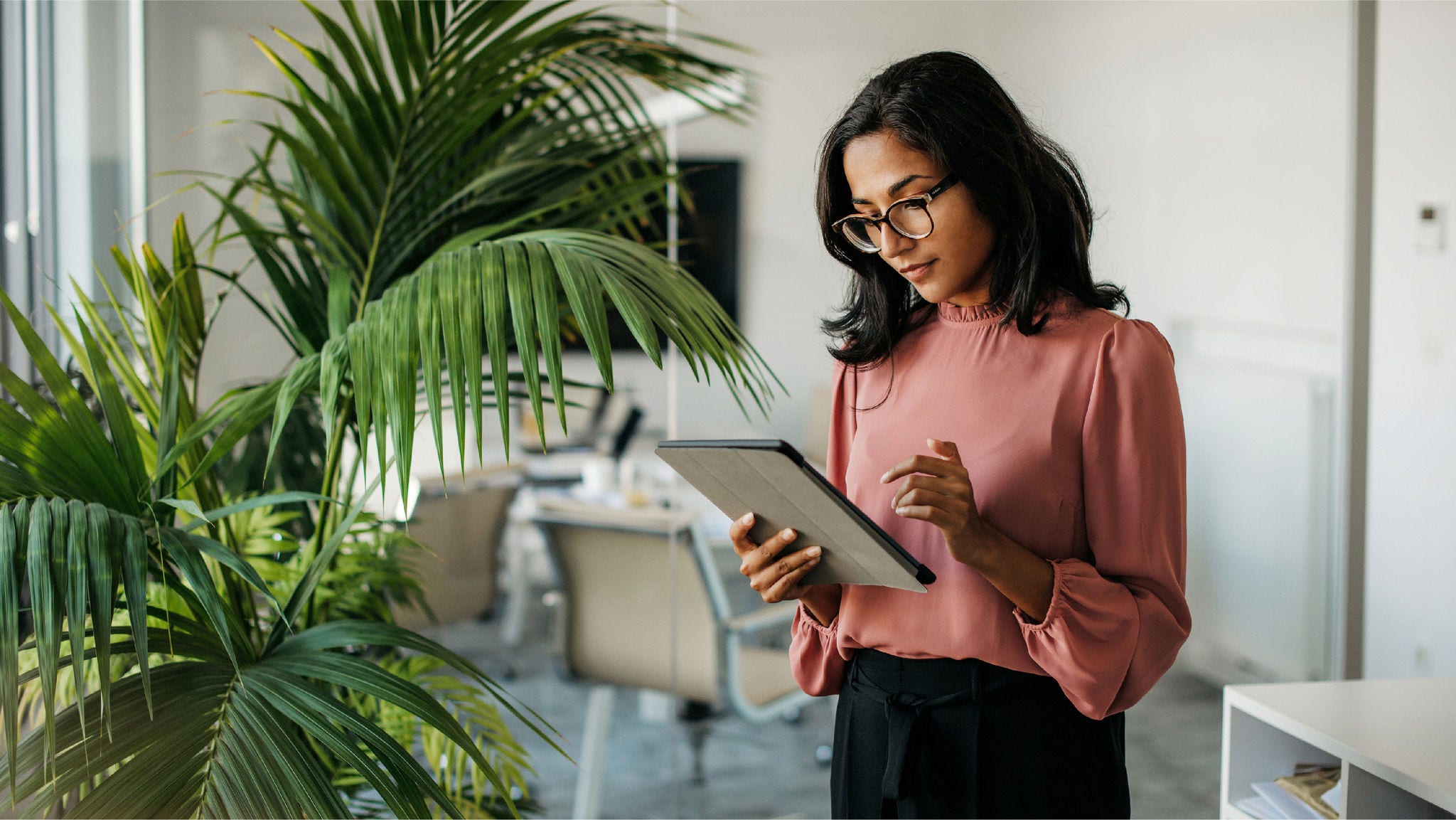 Manager works on a tablet outside of a conference room.