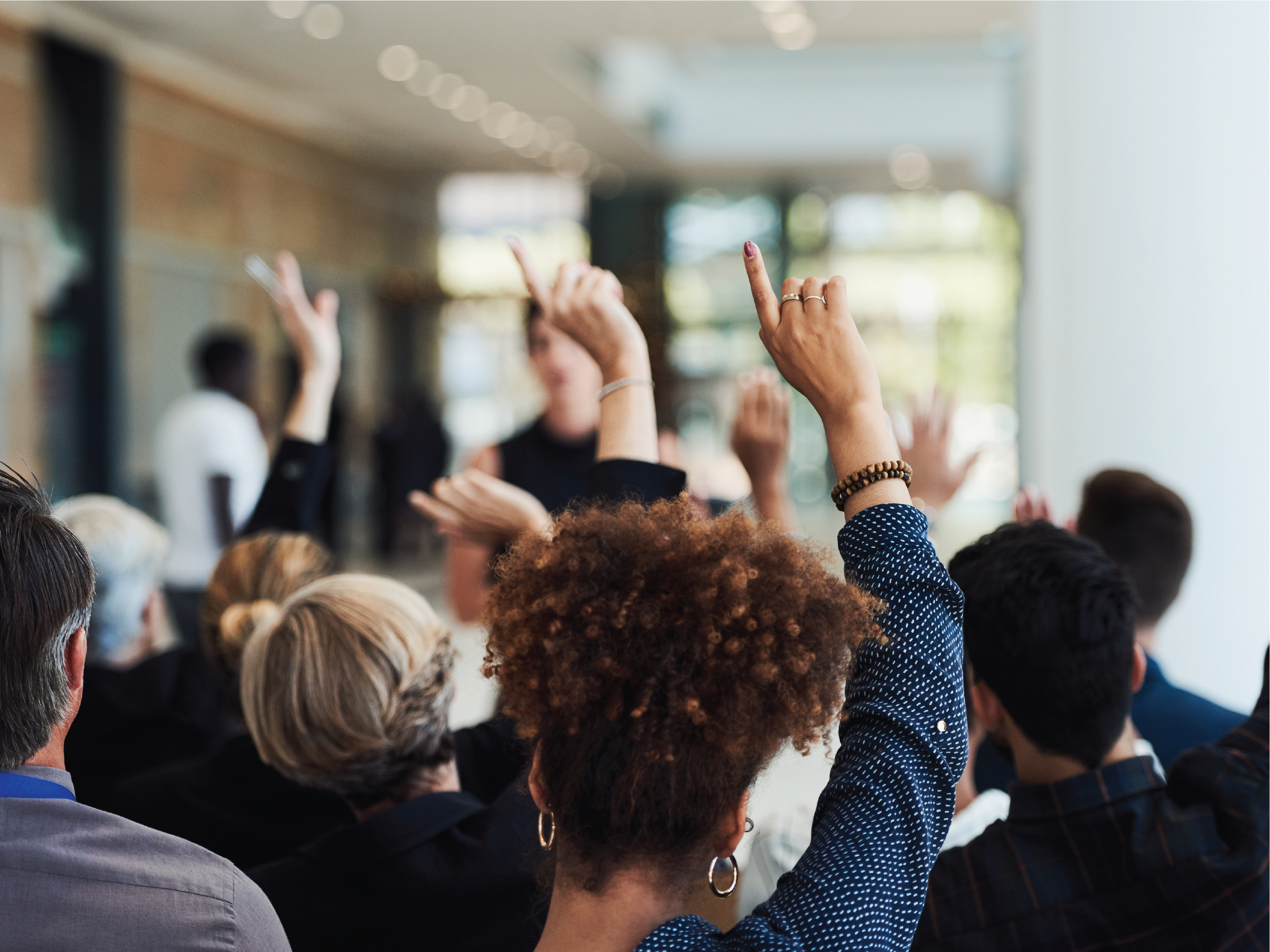 Colleagues in an informational session raise their hands to ask questions