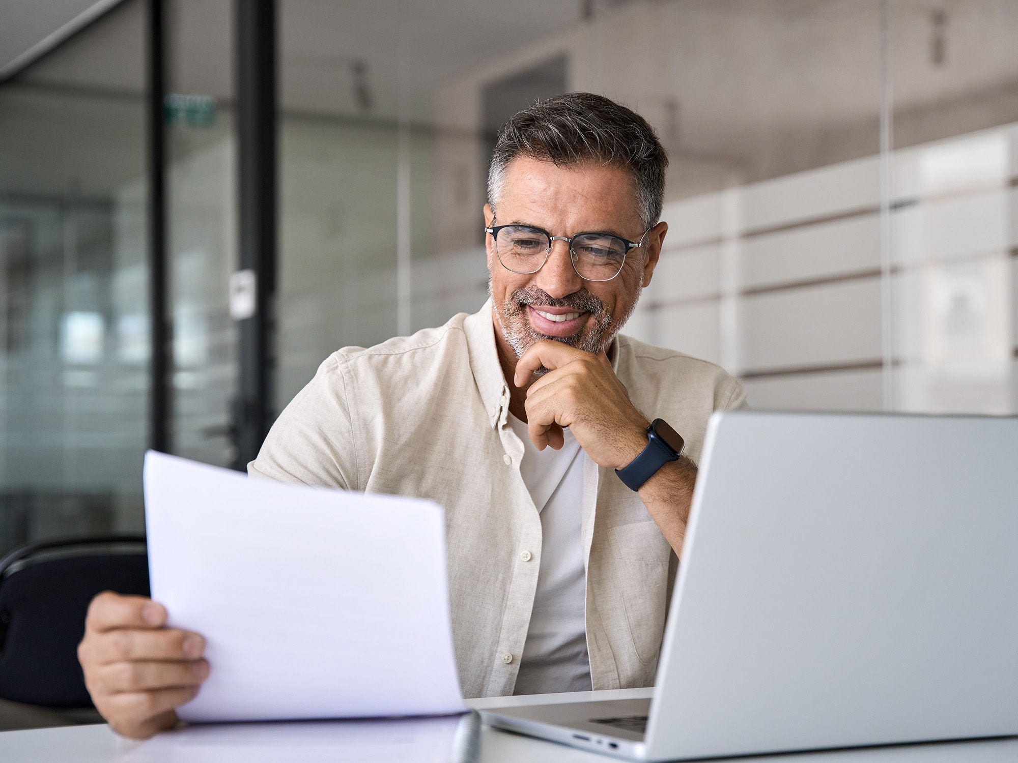 Man smiles at policy while working on his laptop. 