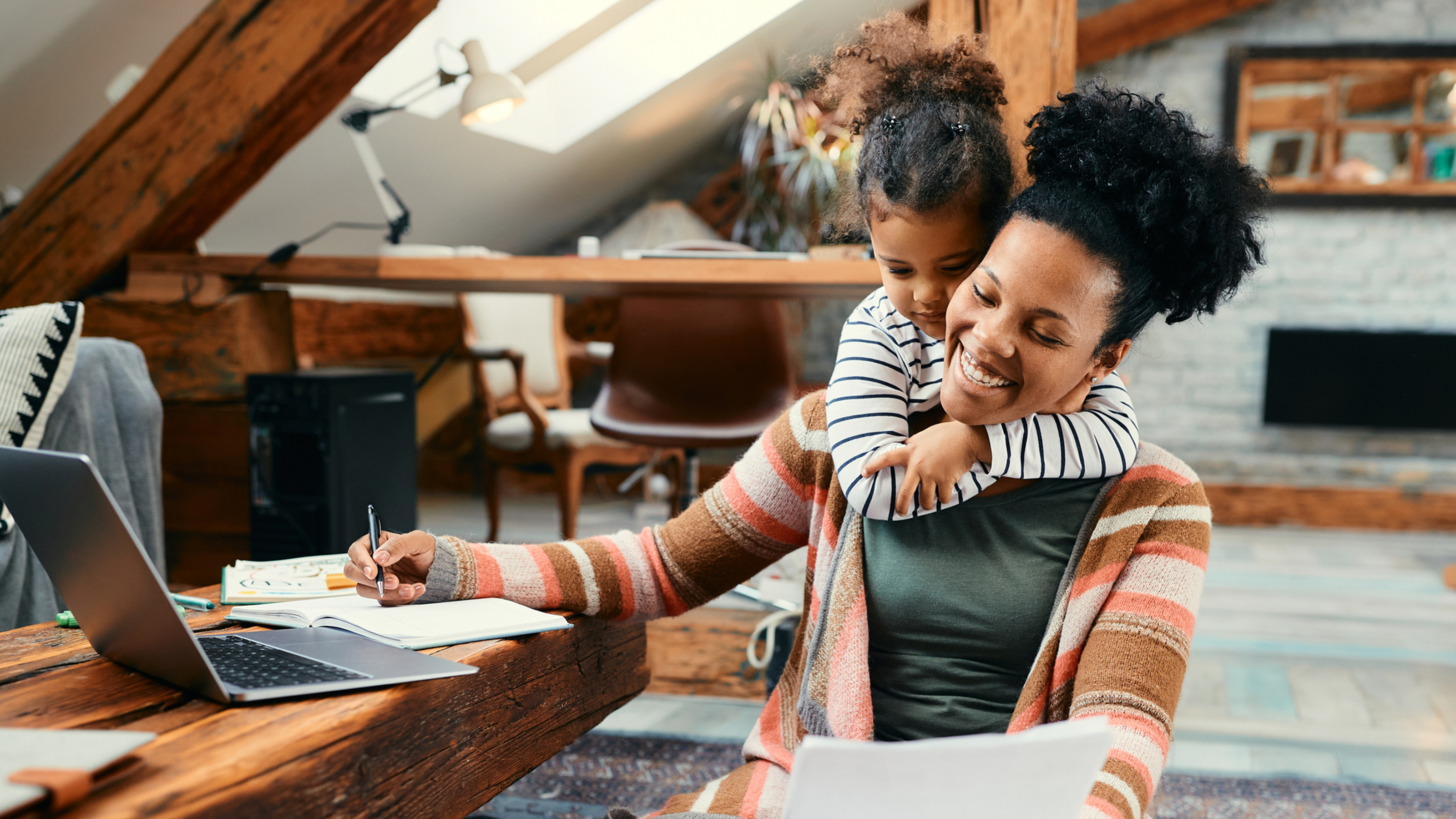 a woman works from home with her daughter on her shoulders