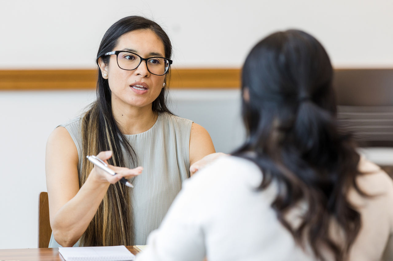 Two seated women have an intense but professional conversation.