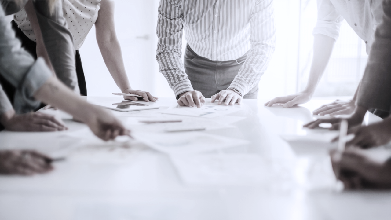 5 business leaders standing around a table planning