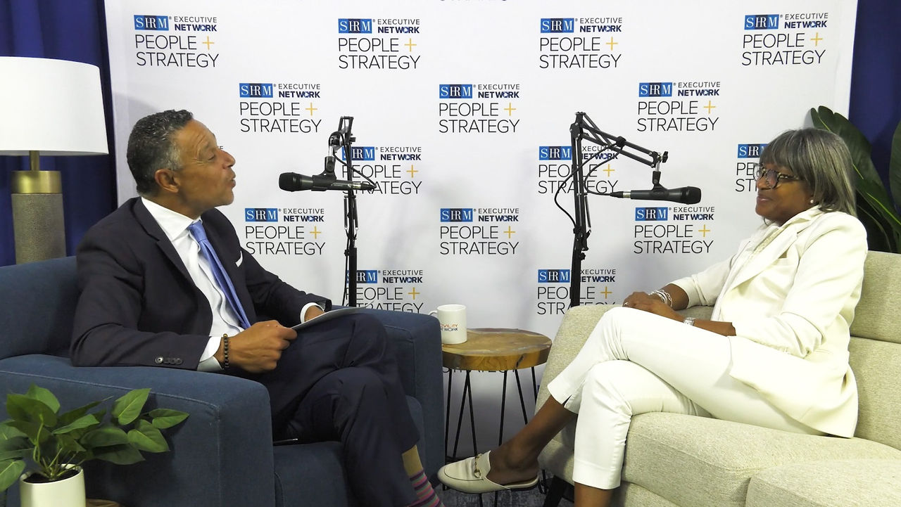 DeRetta Rhodes sitting across from host Mo during the People+Strategy podcast recording.