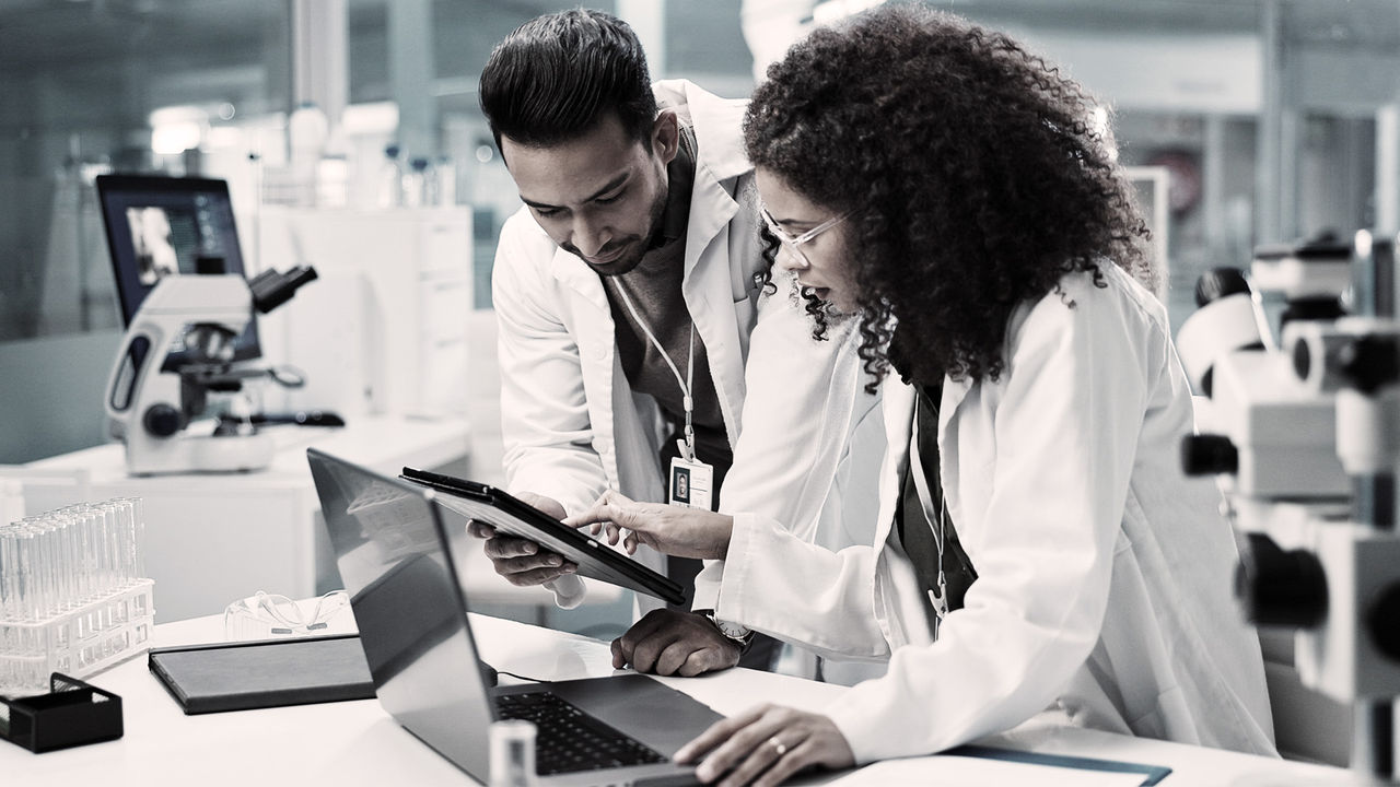 Two colleagues look at a report together in a science laboratory.