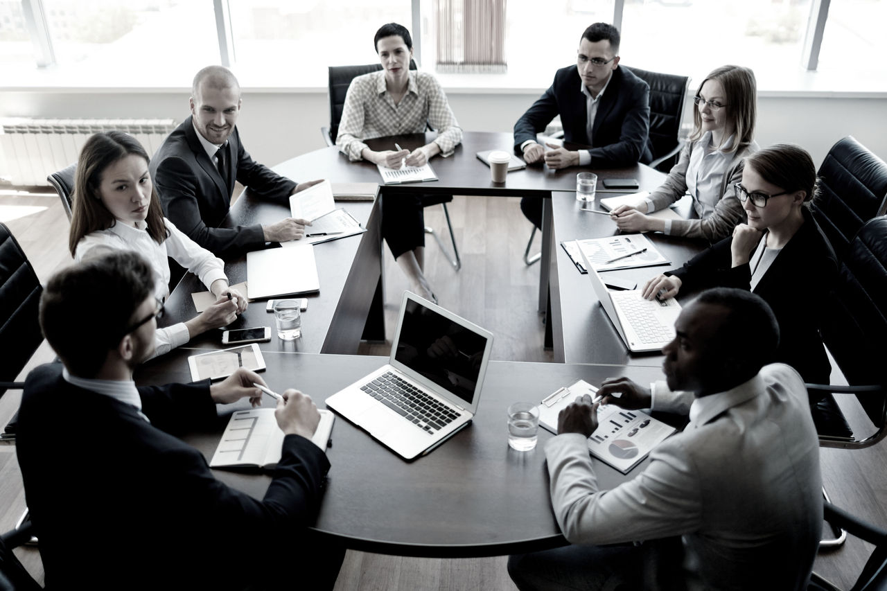 Image of business executives sitting at a circular table for meeting.