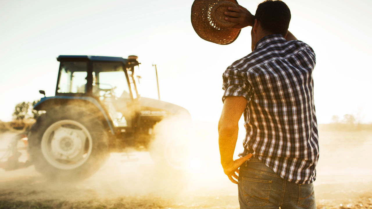 A man in a hat is standing in front of a tractor.