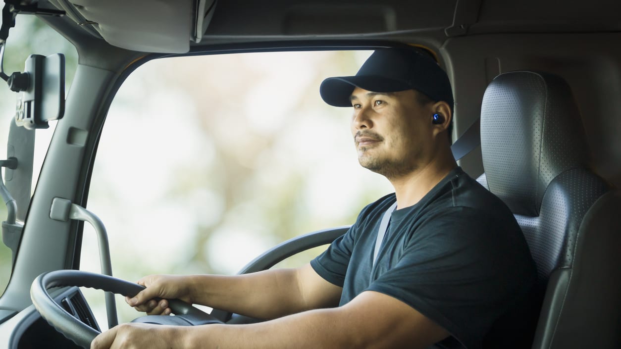 A man driving a truck with headphones on.