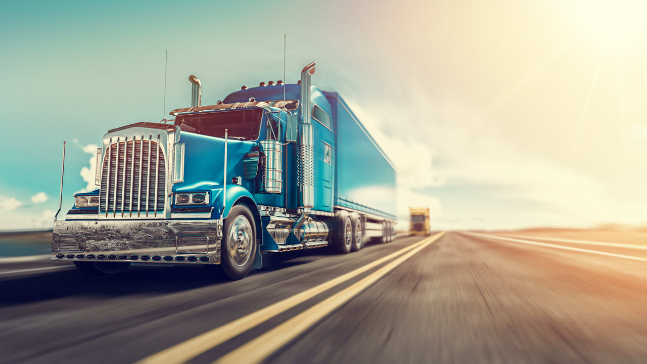 A blue semi truck is driving down the road.