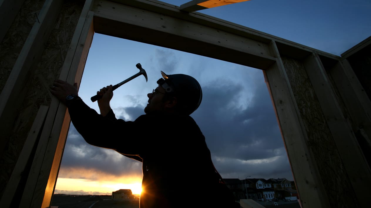 A man hammering a hammer into a wooden frame at sunset.