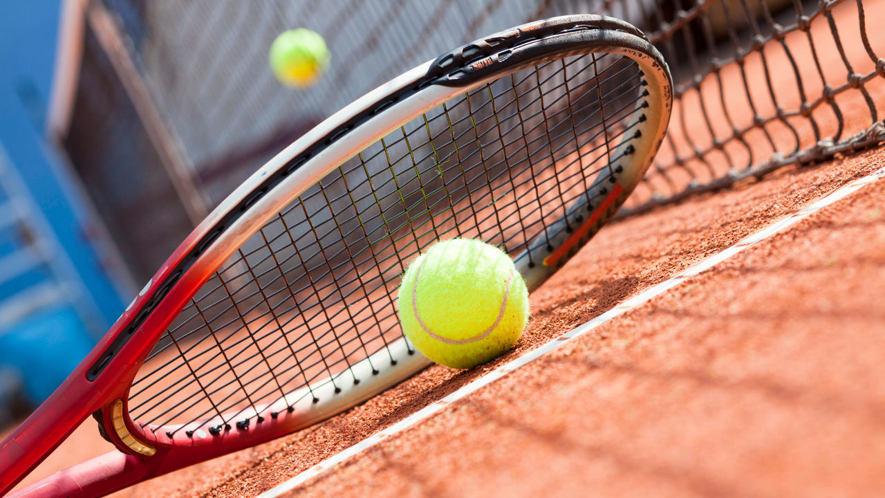 A tennis racket and ball on a tennis court.