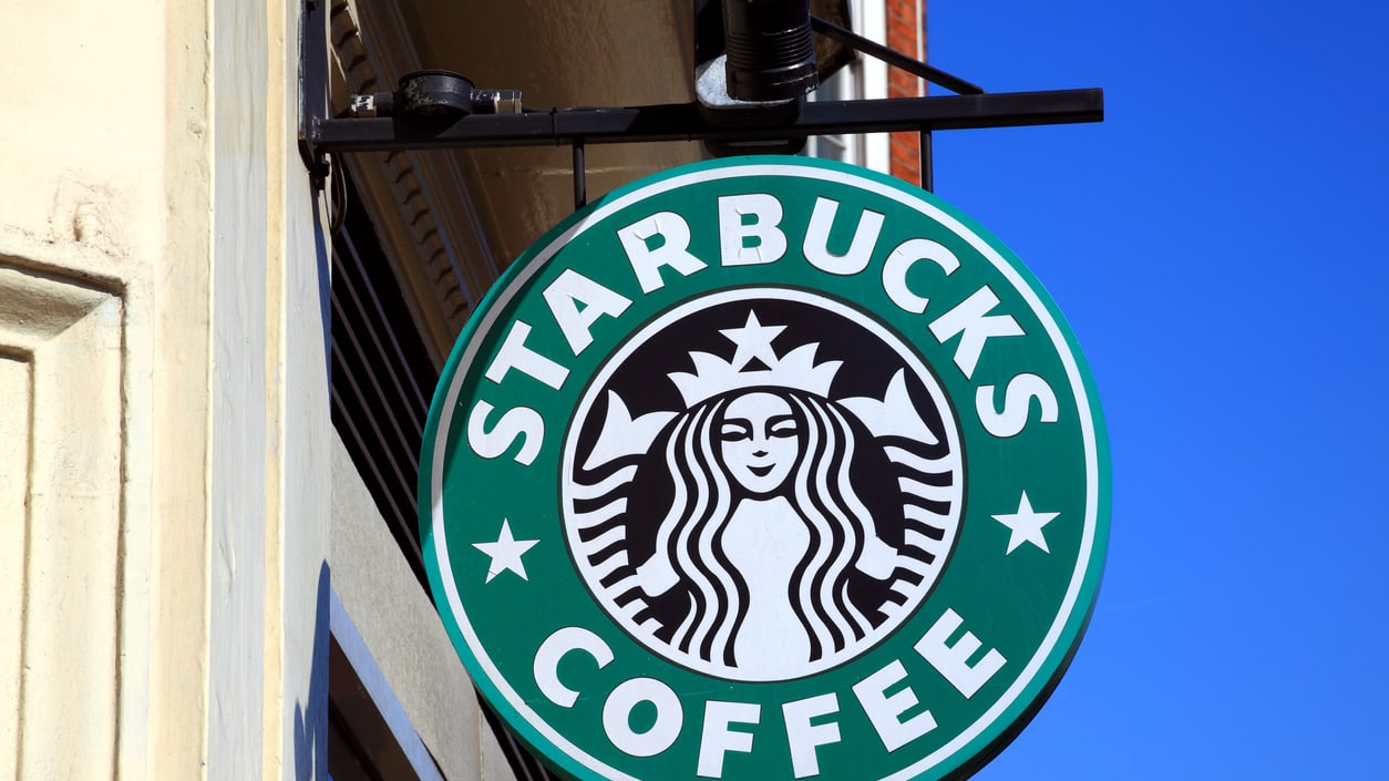 A starbucks coffee sign hanging from a building.