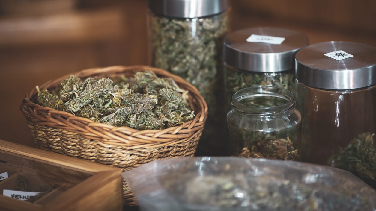 Marijuana in jars and baskets on a table.