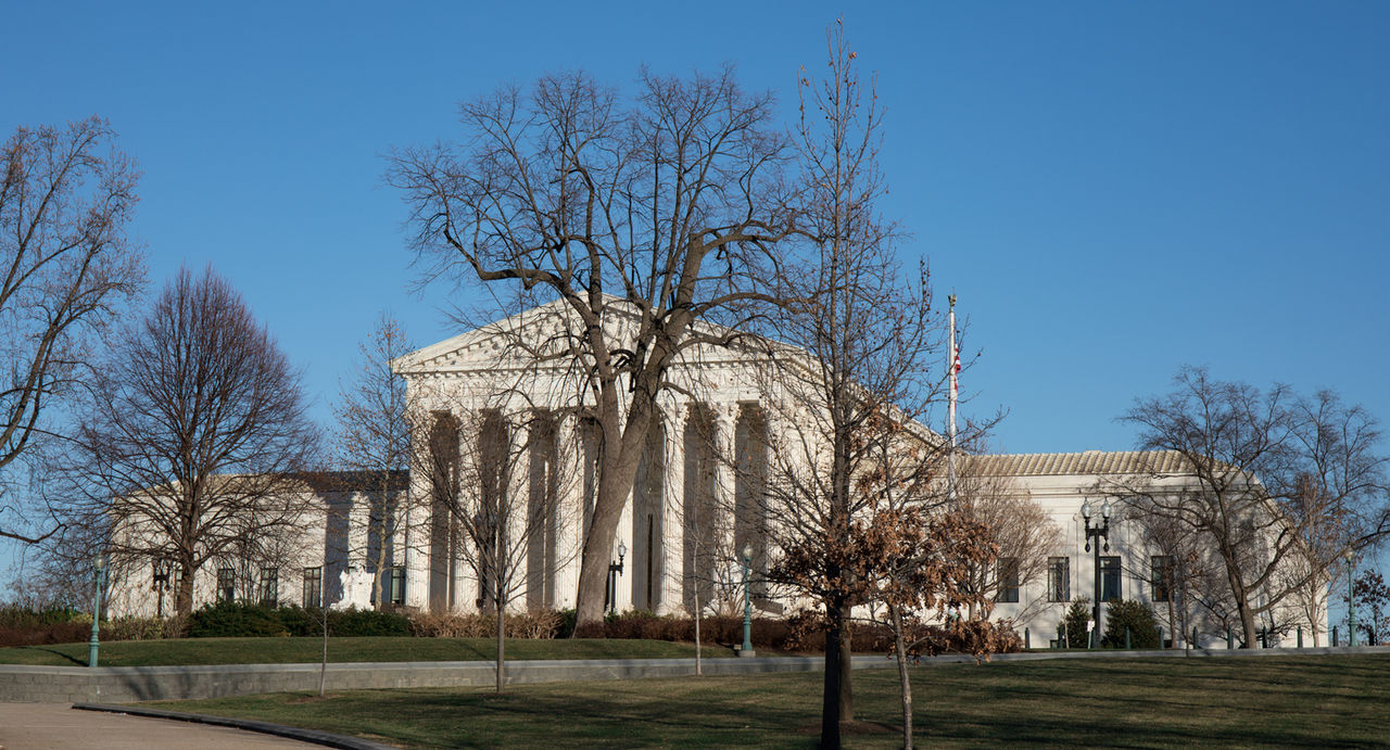 The US Supreme Court in Washington, D.C. with a bright blue sky.