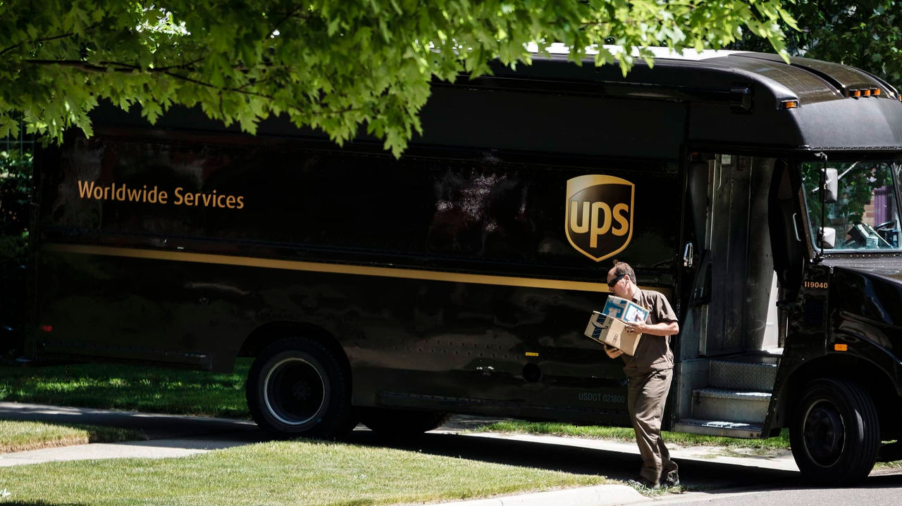 A man is loading a package into a ups truck.