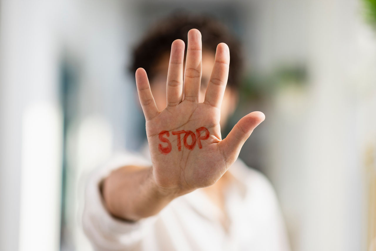 A medium, portrait shot of a man holding his hand out to the camera, written on it is STOP.
