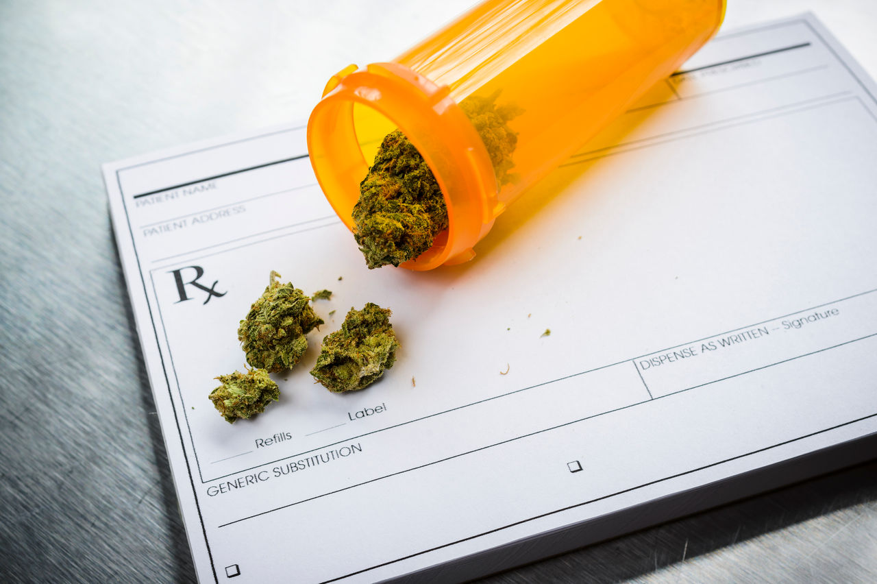 Medical marijuana spilled out of a pill bottle onto a prescription pad.