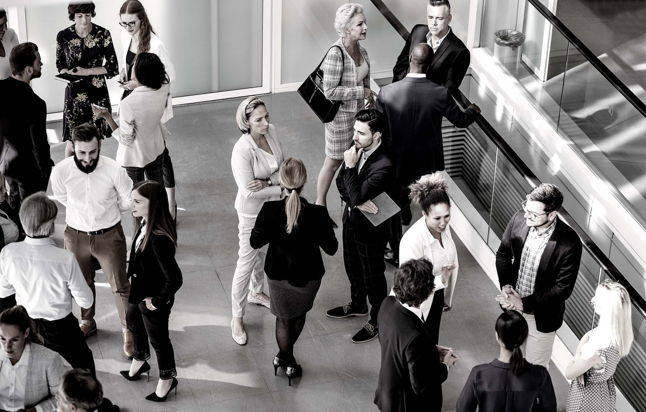An overhead shot of a group of employees from multiple generations  having pleasant discussions about their work.