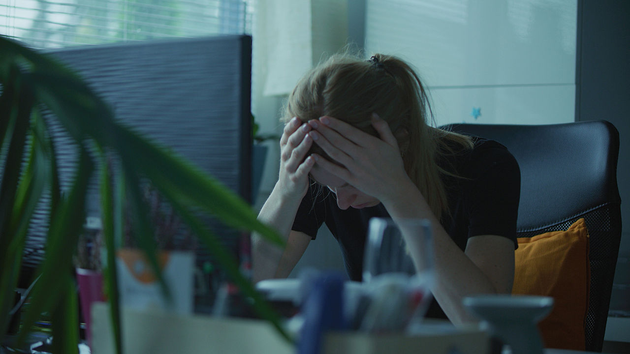A distraught worker with hands to her head at her computer