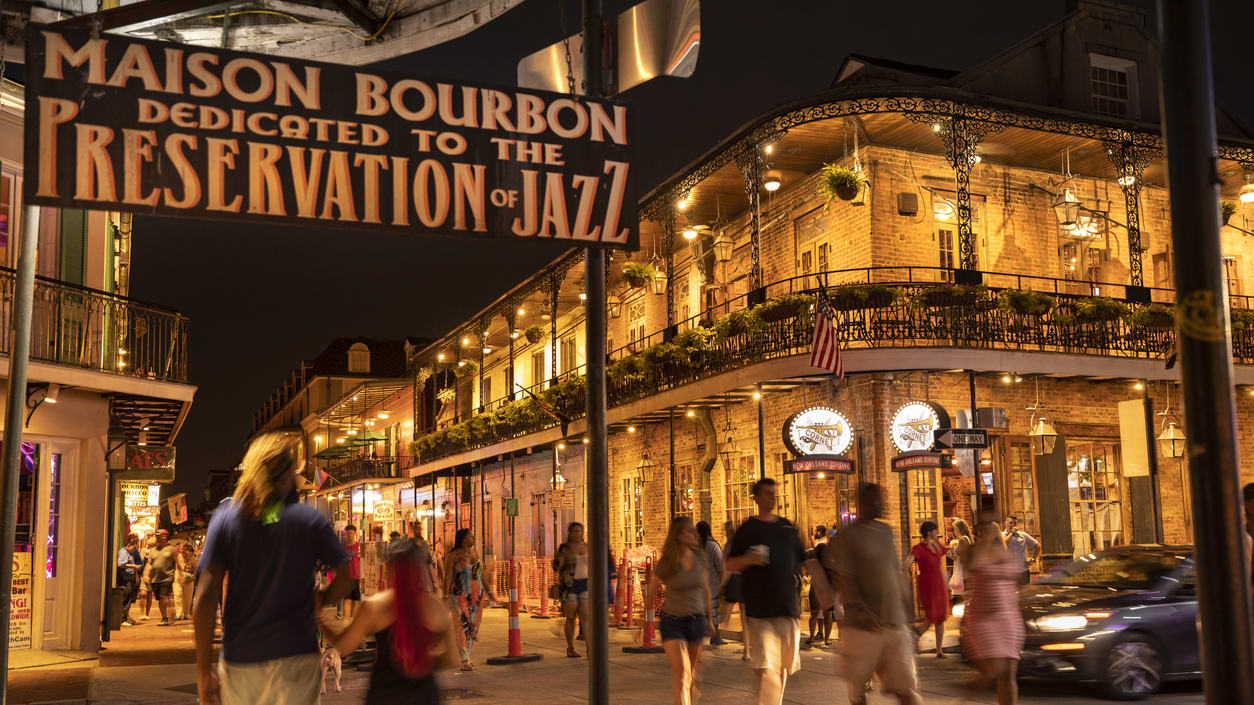 A group of people walking down a street in new orleans at night.