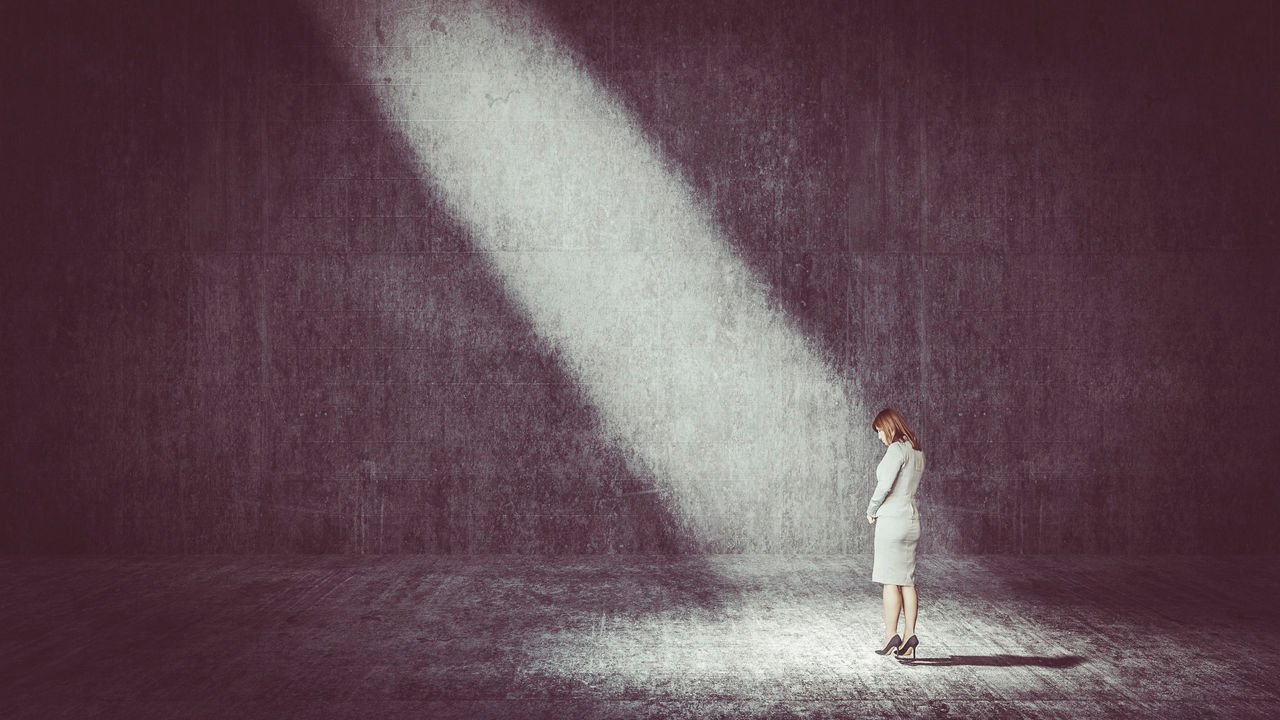 A business woman standing in front of a light beam.