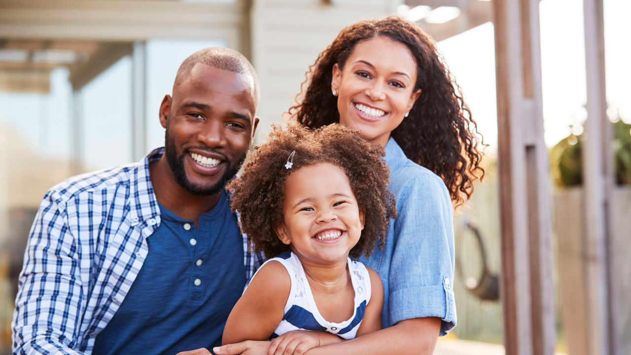 An african-american family is smiling while sitting on a porch.