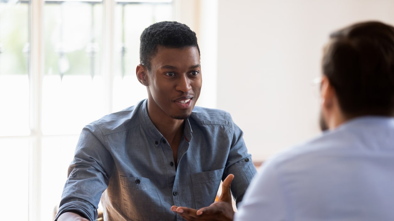 A group of people sitting at a table talking to each other.