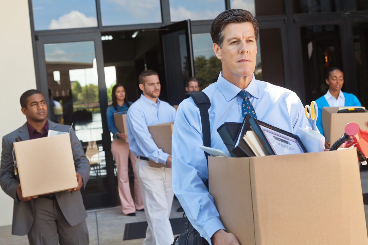 Laid off workers leaving an office building carrying boxes of personal belongings