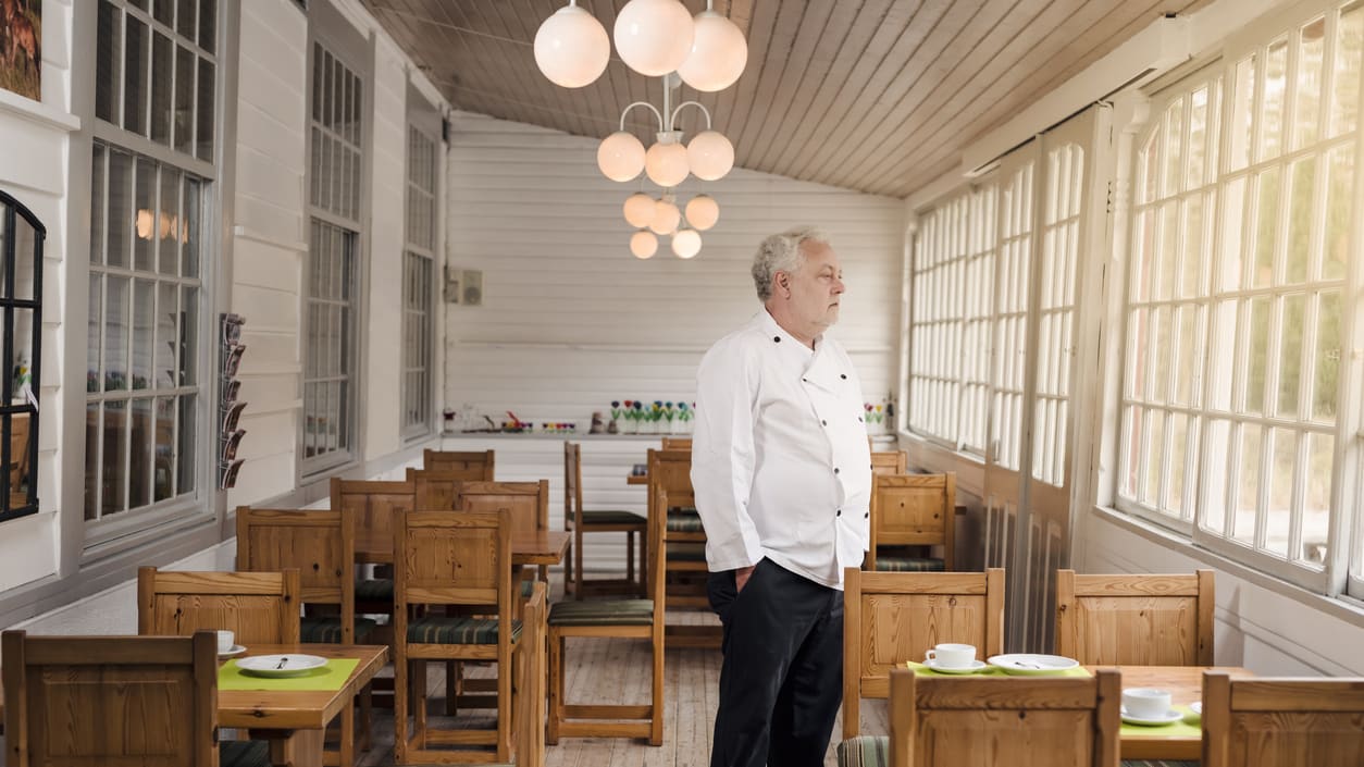 A man in a chef's uniform standing in a restaurant.