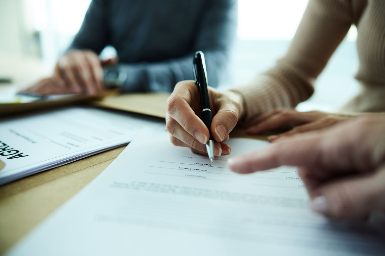 Close up of unrecognizable woman signing a contract in the office.