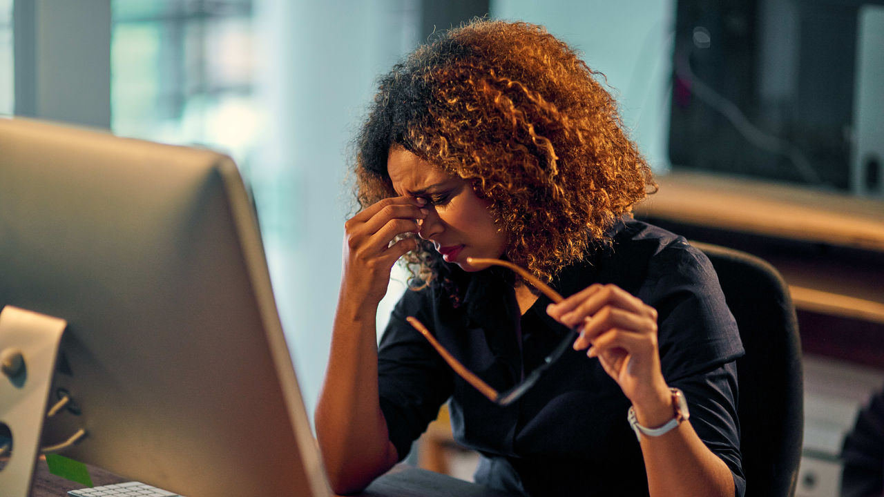 A woman is sitting at a desk looking at her computer screen.