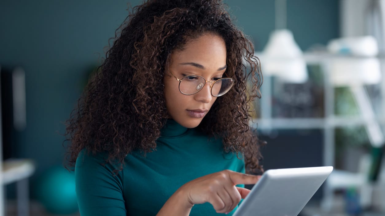 A woman wearing glasses is using a tablet computer.