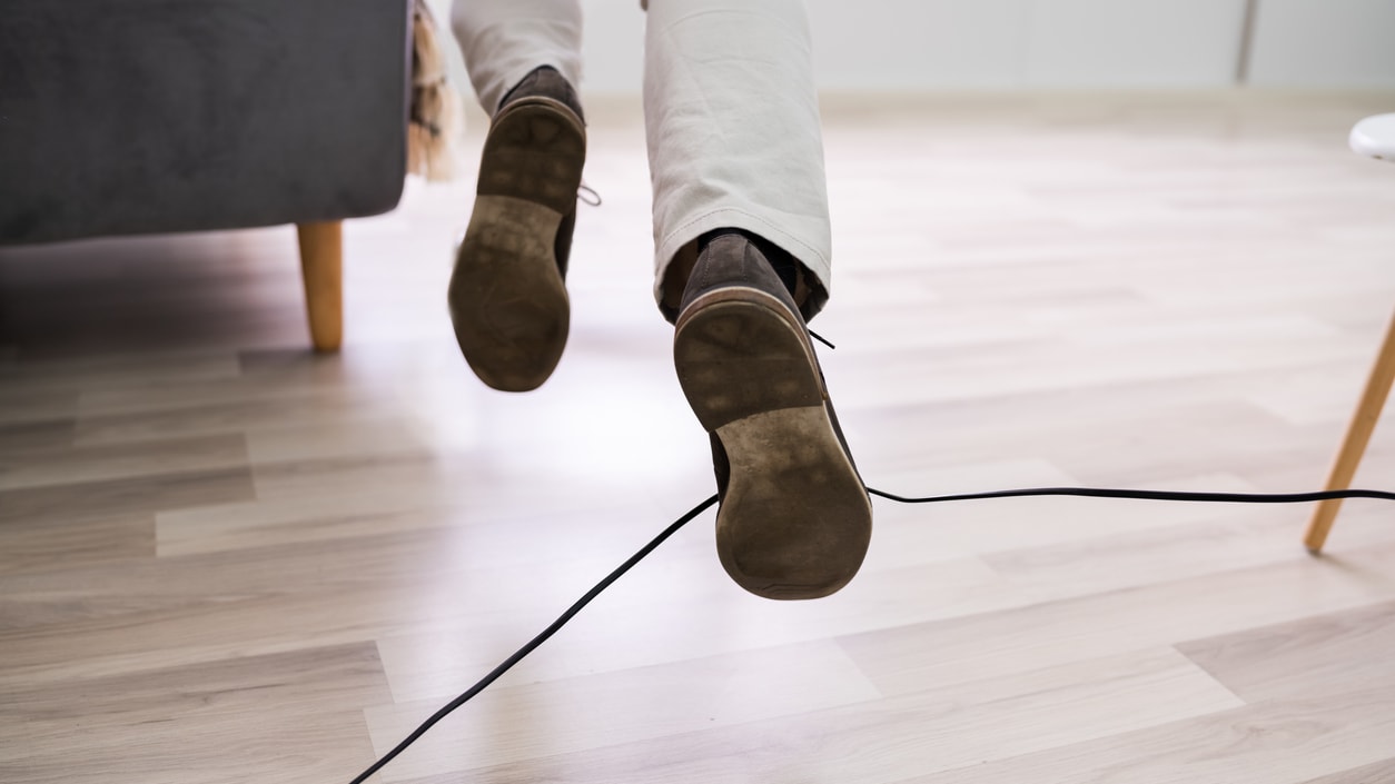 A man is jumping over a cord in a living room.