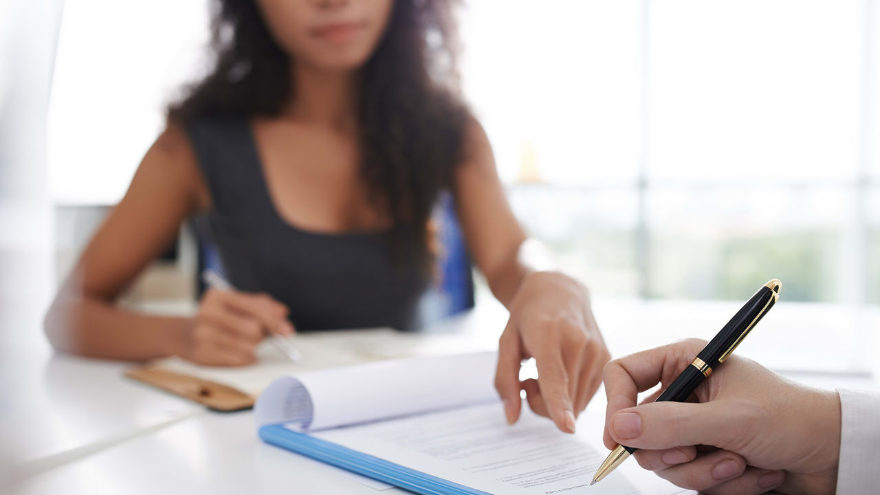 A woman signing a document with a pen.