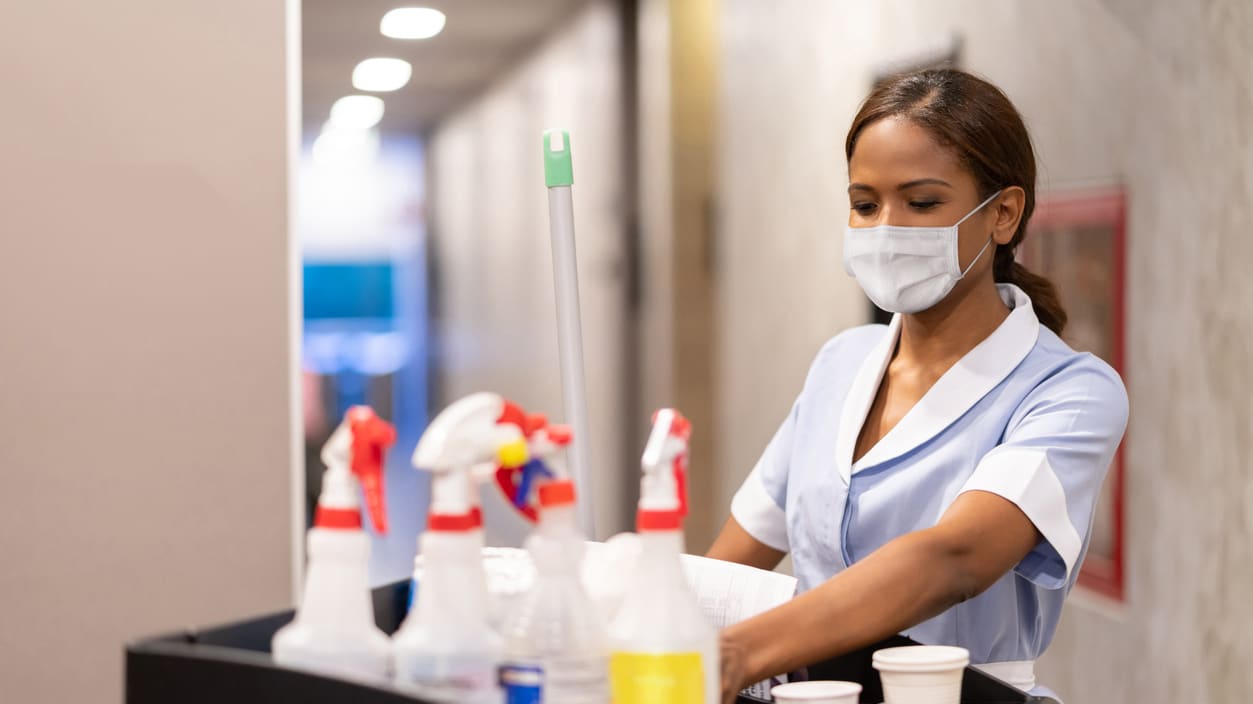 A woman wearing a mask is cleaning a table in a hospital.