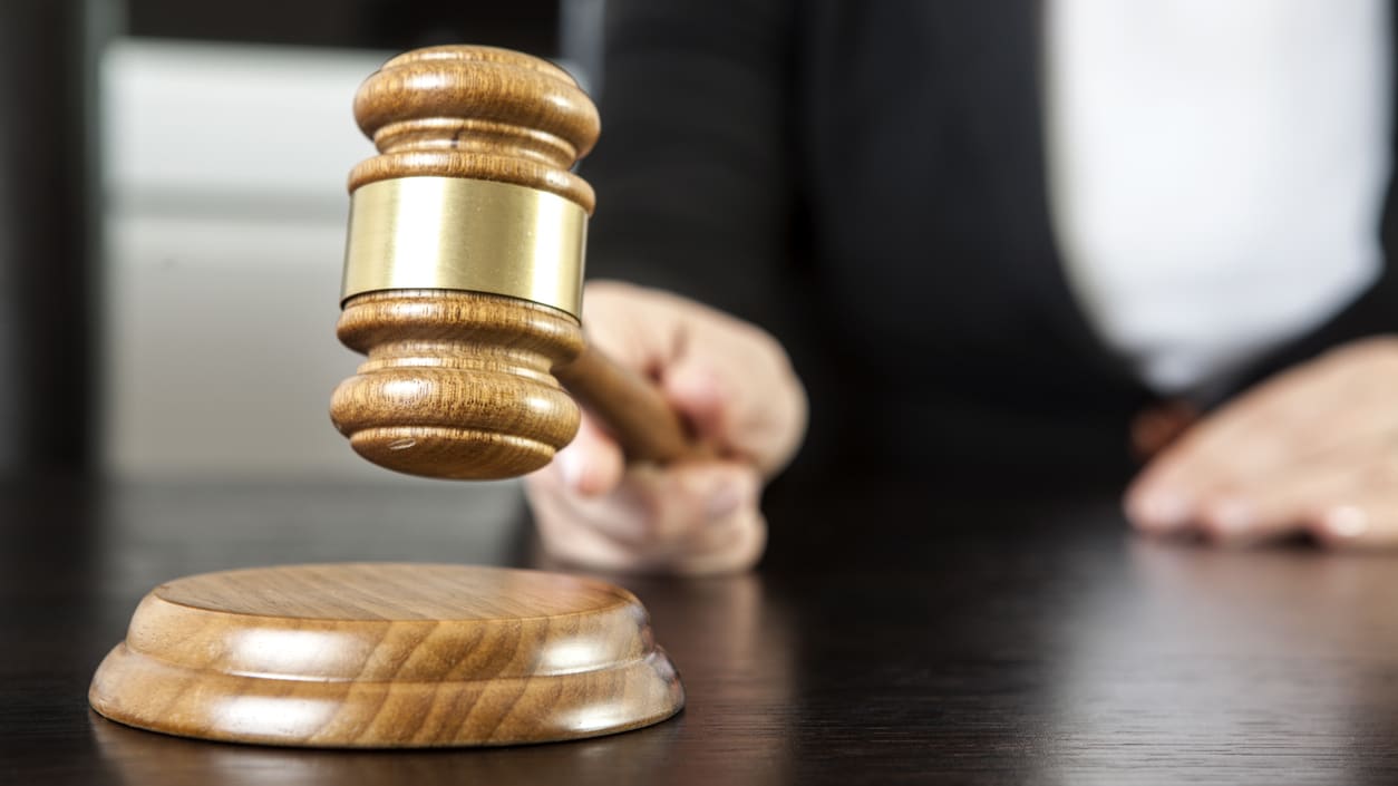 A woman is holding a wooden gavel on top of a table.