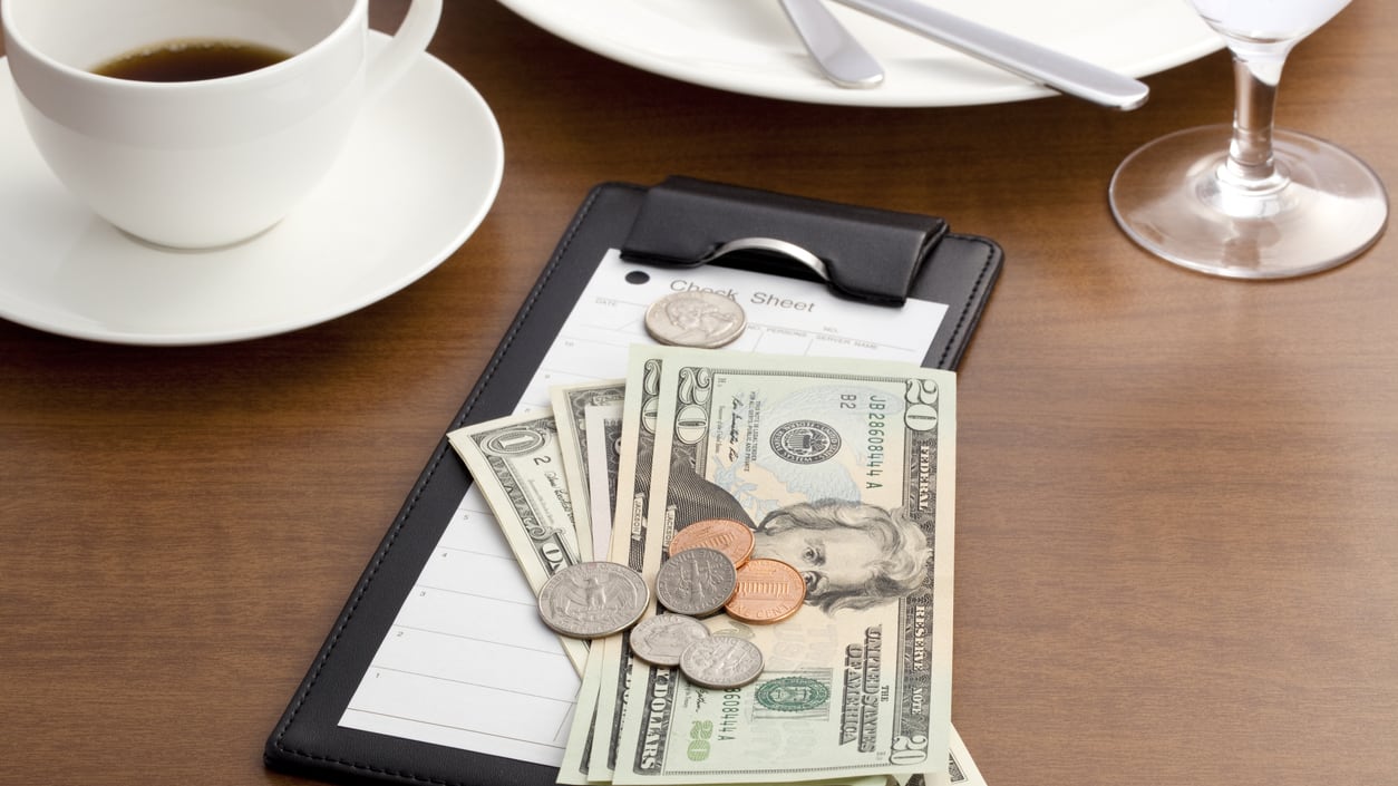 A clipboard with money and a cup of coffee on a table.