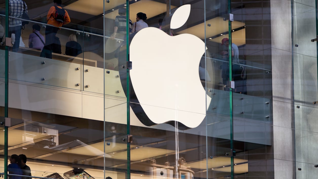 An apple logo is seen on the glass of an apple store.